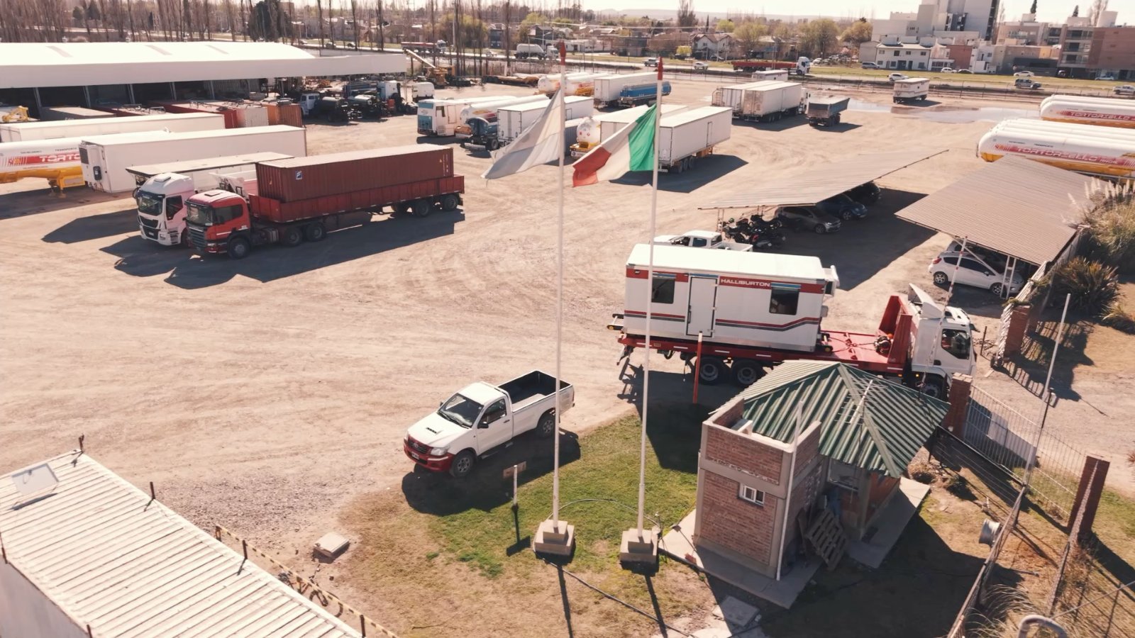 Vista aérea de la base operativa de FAMACRI con camiones, trailers y una cabina de trabajo cargada