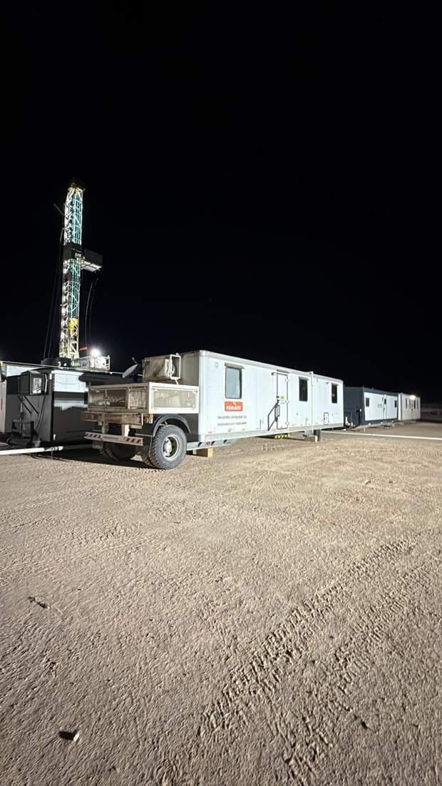 Trailer habitacional junto a equipo de perforación en operación nocturna